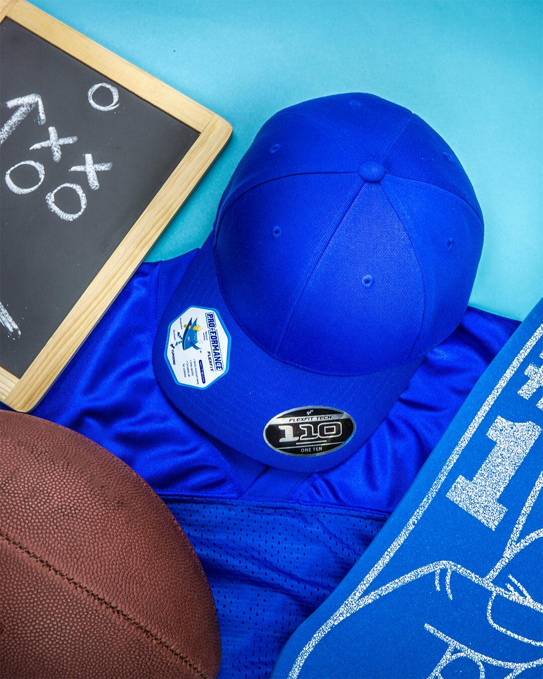 Blue cap with a logo, blue shirt, and football on a blue background